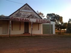 an old building sitting in the middle of a dirt road