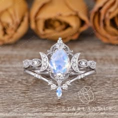 a white gold ring with an oval cut rainbow stone surrounded by small diamonds on a wooden surface