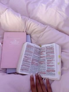 a person is laying in bed with an open book on their lap and the pages are pink