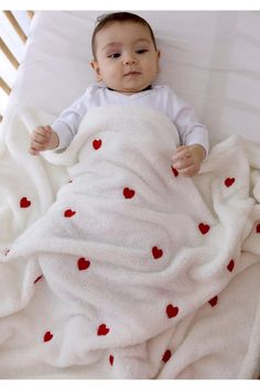 a baby wrapped in a blanket with hearts on it