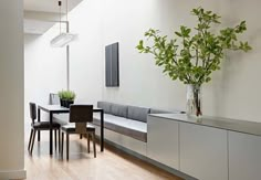 a dining room table with chairs and a plant in a vase on top of it