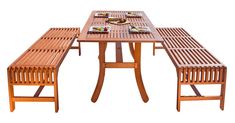 a wooden table with two benches next to it and plates on the table in front of it