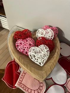 several hearts are placed in a bowl on a table with red and white doily