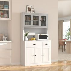 a kitchen with white cabinets and wooden floors