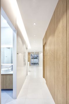 an empty hallway leading to a bathroom with wooden walls and white tile flooring on both sides