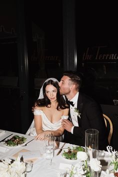 a bride and groom sitting at a dinner table