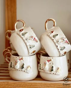 four white ceramic cups with gold handles and snowmen on them