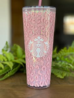 a pink starbucks cup sitting on top of a wooden table