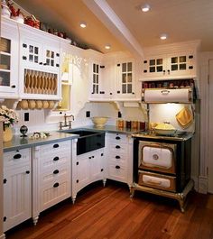 a kitchen with white cabinets and wood floors