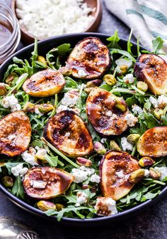 a salad with figs and feta cheese in a black bowl on a table