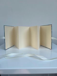 an open book sitting on top of a white table next to a ribbon tied around it