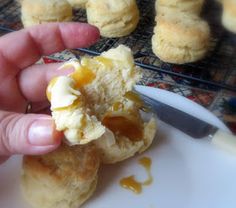 a person is holding an open biscuit in front of some biscuits on a cooling rack