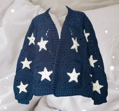 a blue crocheted sweater with white stars on the front and back, laying on a bed