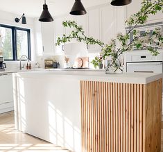 a kitchen with white cabinets and black pendant lights hanging from the ceiling over the island