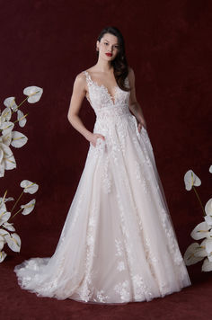 a woman in a wedding dress posing for the camera with white flowers behind her on a red background