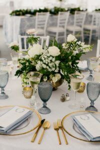 the table is set with silver and gold place settings, white flowers in vases