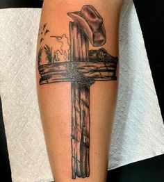 a cross with a cowboy hat on it and birds flying around the cross tattoo design