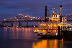 a large boat floating on top of a body of water near a bridge at night