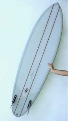 a person holding a surfboard up to the wall in front of their head and hand