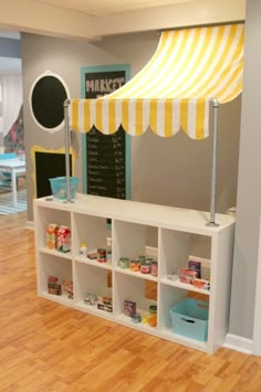 a child's playroom with toys and bookshelves in the corner, under a yellow striped awning