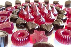 many different types of chocolates are arranged on a white tablecloth with red ribbons