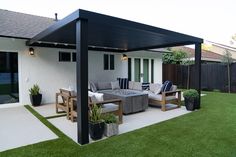 an outdoor living area with couches, tables and potted plants on the grass