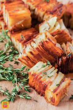 some food that is laying out on a cutting board next to rosemary sprigs