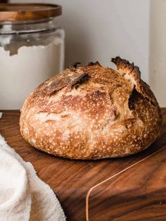 a loaf of bread sitting on top of a wooden cutting board next to a jar