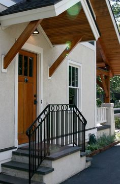 a white house with stairs leading up to the front door and entry way that has a black iron hand rail