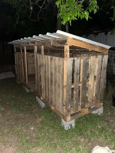 a dog laying in the grass next to a wooden structure with chicken cages on top