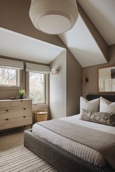 a large bed sitting under a window next to a dresser in a room with white walls