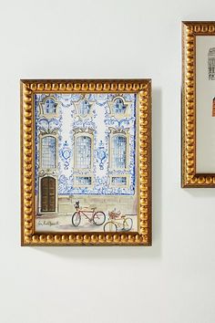 two framed pictures hang on the wall next to each other, one with a bicycle painted on it