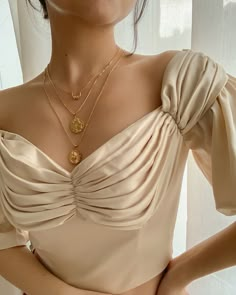 a close up of a woman wearing a dress with a gold necklace on her neck