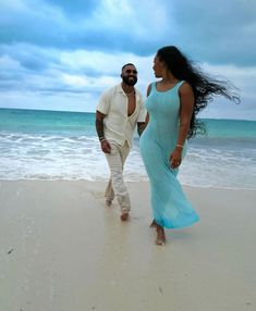 a man and woman are walking on the beach