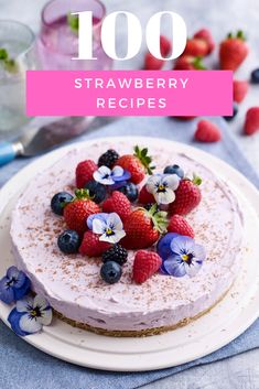 there is a cake with berries and blue flowers on the top, next to a glass of water