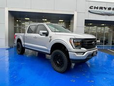 a white truck is parked in front of a dealers showroom with blue flooring