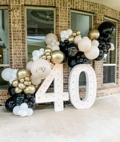 the number forty is decorated with balloons and streamers in gold, black, and white