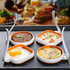 four different bowls with food in them sitting on a tray next to some bread and eggs