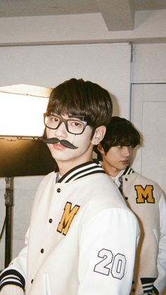 two young men with fake moustaches on their faces are standing next to each other