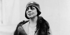 an old black and white photo of a woman wearing a fur coat with a hat on her head