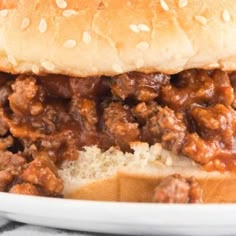 a close up of a sandwich on a plate with meat and bread in the background