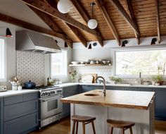 a large kitchen with an island in the middle and two stools at the counter