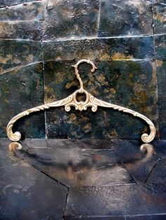 an ornate gold coat hanger on a stone wall