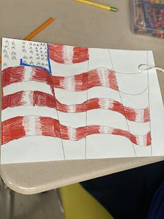 a child's drawing of an american flag on a piece of paper with colored pencils