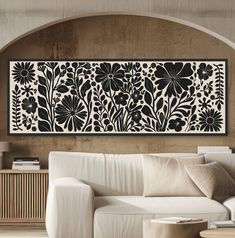 a living room with a white couch and black floral wall art on the wall above it