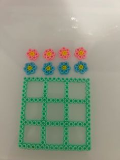 an object made out of plastic beads with flowers on the top and one flower at the bottom