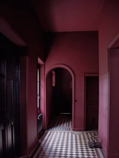 an empty hallway with checkered floor and red walls