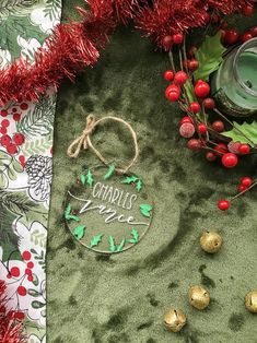 a christmas ornament with holly and red berries on a green velvet tablecloth