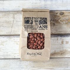 a brown paper bag filled with nuts on top of a wooden table