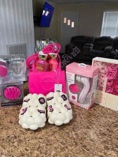 baby shoes and other items are sitting on the counter in front of a pink bag